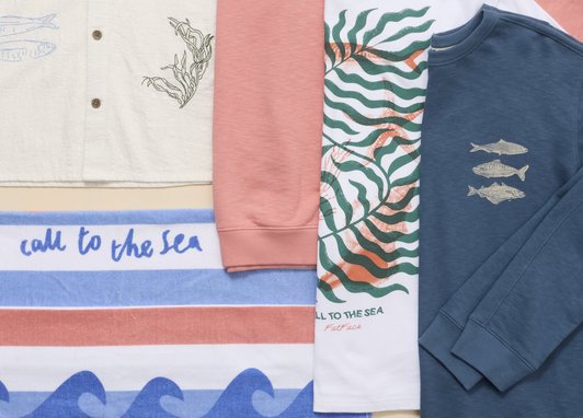 Clothes from the Fatface X Marine Conservation Society 2026 collection laid flat. The towel reads 'call to the sea'.