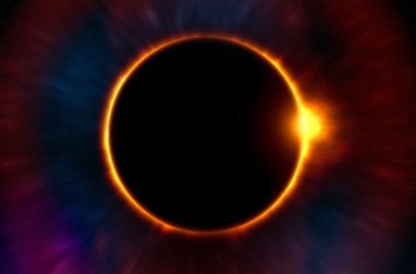 The sun is covered by the moon in a solar eclipse event. a bright orange circular line is glowing behind the moon.