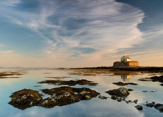This image shows St Cwyfan's Church, commonly known as the "Church in the Sea," located on the tiny island of Cribinau off the coast of Anglesey, Wales.