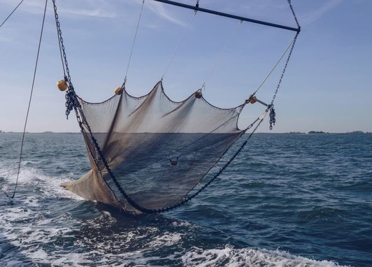 A trawler net is hanging just above the ocean