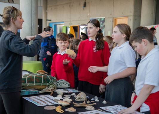 Students learning about various marine artifacts like seashells and fossils at a Marine Conservation Stall.