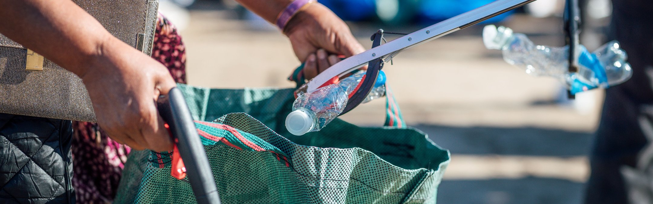 A close up of volunteers filling a bag with plastic bottles at a Scarborough beach clean.