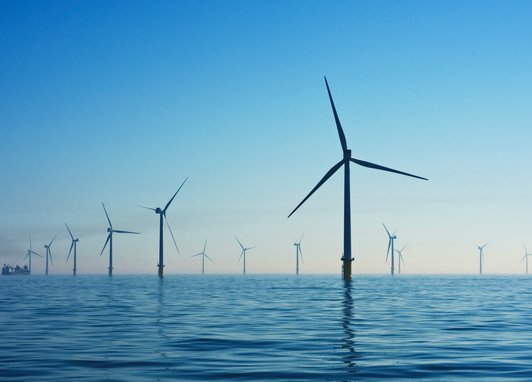 Wind turbines in water at Rampion Offshore Wind Farm, United Kingdom, with blue skies above the water