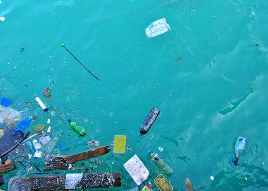 A variety of single-use plastic litter including bottles and cartons are floating in the ocean