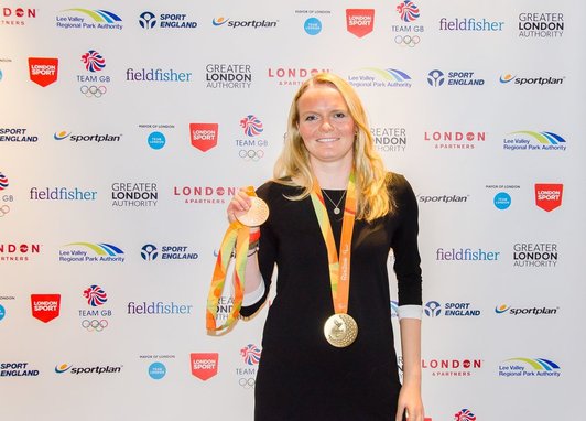 Ocean Ambassador Susie Rodgers stands holding a medal, smiling at the camera