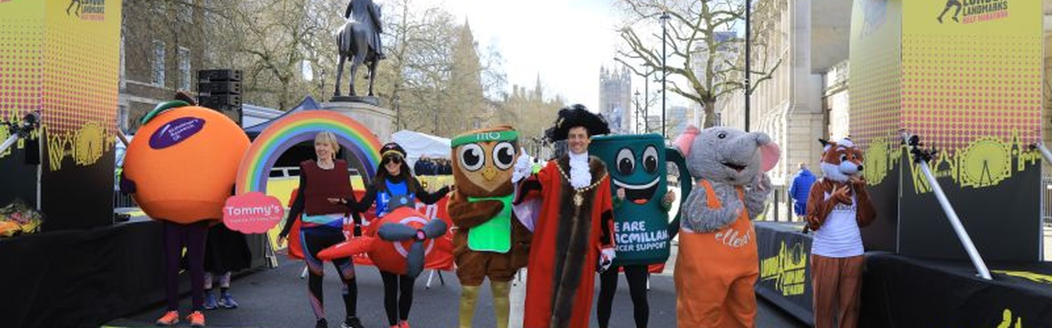Runners in fancy dress costumes are stood underneath the finish line of the London Landmarks Half Marathon.