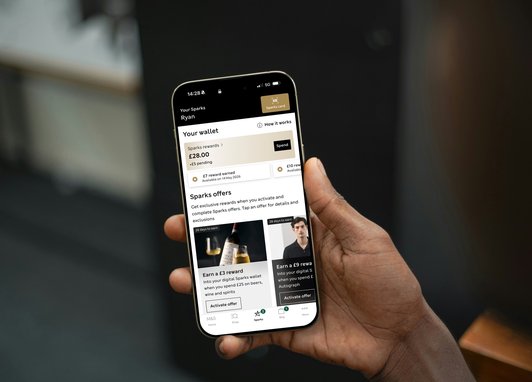A phone being held up. The Sparks app can be see on the screen.