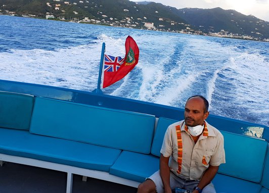 UKOT Conservation Officer Amdeep Sanghera sitting on a ferry as it pulls away from an island