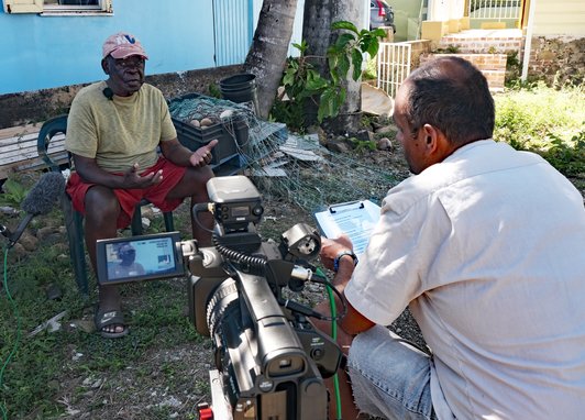 Amdeep interviewing a fisher in Road Town, Tortola for the STEEL Community Voice Method. The camera can be seen.