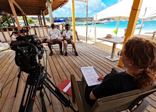 A man and child are sitting on chairs with a camera pointing at them