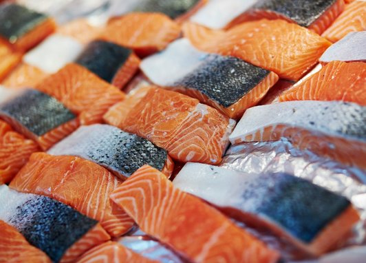 Lots of raw salmon fillets are placed on a bed of crushed ice