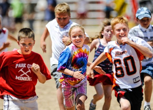 A group o children running on a race track. They are participating in a race