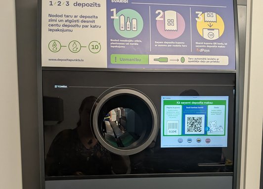 A shot of a reverse vending machine at the Deposit Return Centre in Latvia. A description of how to use it is clear on the top of the machine.