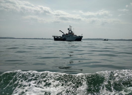 A small white fishing boat is photographed floating in the sea