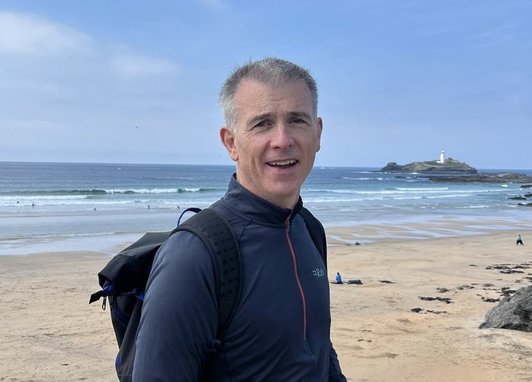 David Wilkin, the Marine Conservation Society's Treasurer, stands on a beach smiling at the camera