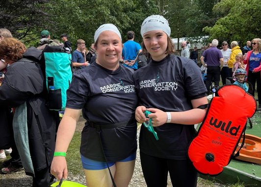 2 swimmers posing for a photo wearing MCS branded clothes