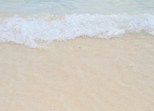 A white snay beach with waves breaking at the top of the image